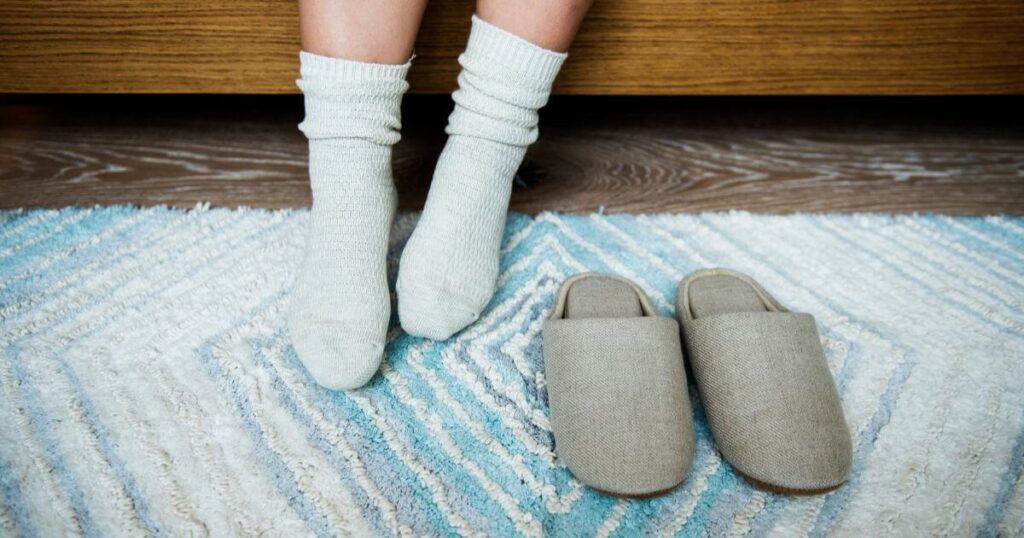 person-waking-up-with-cozy-slippers-next-to-bed